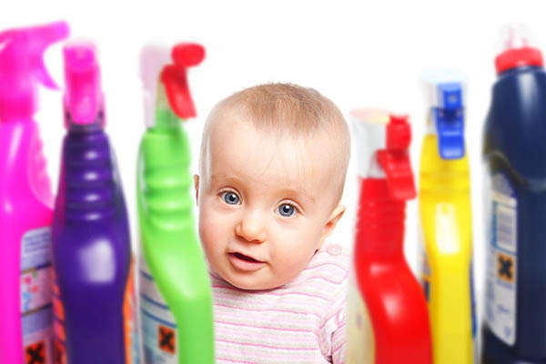 Bebé perto de frascos de detergente
