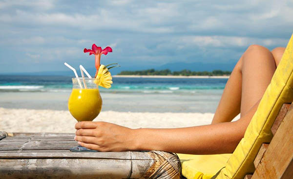 Mulher na praia com sumo de frutas