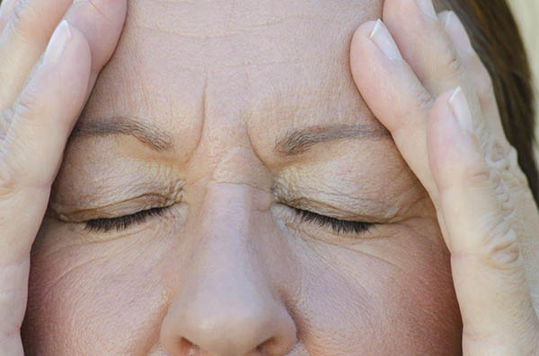 Mulher de olhos fechados com dor de cabeça