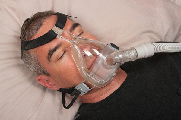 Homem a dormir com máscara para apneia do sono