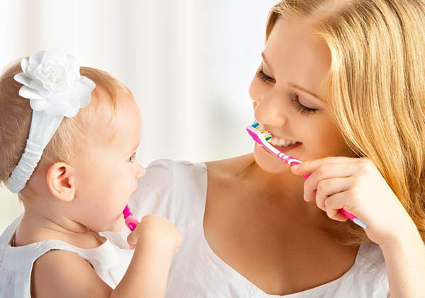 Mãe ensina filha a lavar os dentes