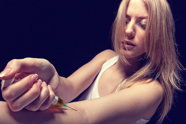 Mulher a injectar heroína no braço