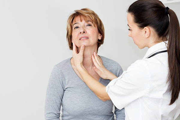 Médica examina pescoço de mulher