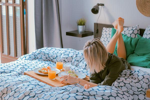 Mulher deitada na cama a tomar pequeno almoço