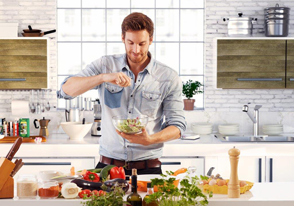 Homem na cozinha a temperar salada