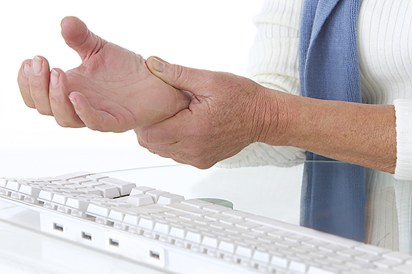 Homem ao computador com dor no pulso