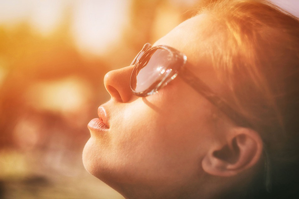 Mulher com óculos de sol a olhar para o céu