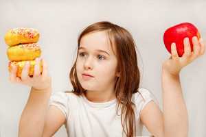 Criança indecisa entre donuts e maçã