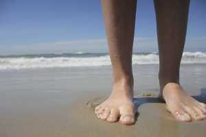 Pés descalços na praia à beira mar