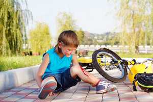 Rapaz a sangrar do joelho após queda de bicicleta