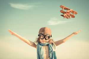 Criança com óculos de aviador a brincar aos aviões