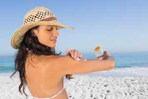 Mulher na praia a aplicar protetor solar